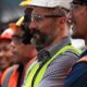 a row of blue collar workers in hard hats is smiling