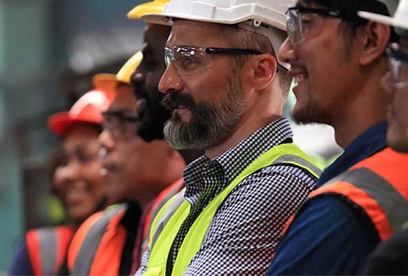 a row of blue collar workers in hard hats is smiling